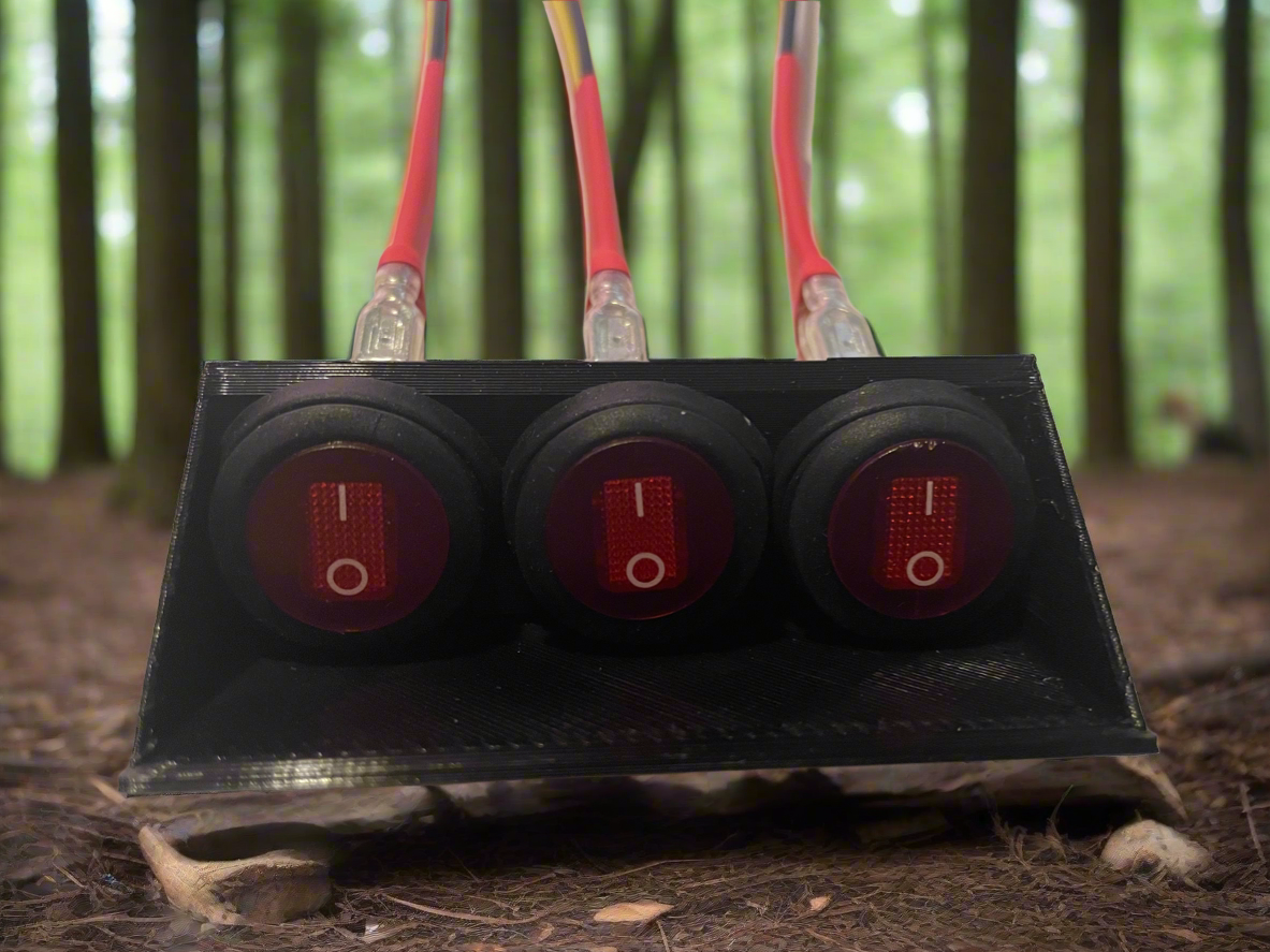 Triple toggle switch panel with red switches and wiring.