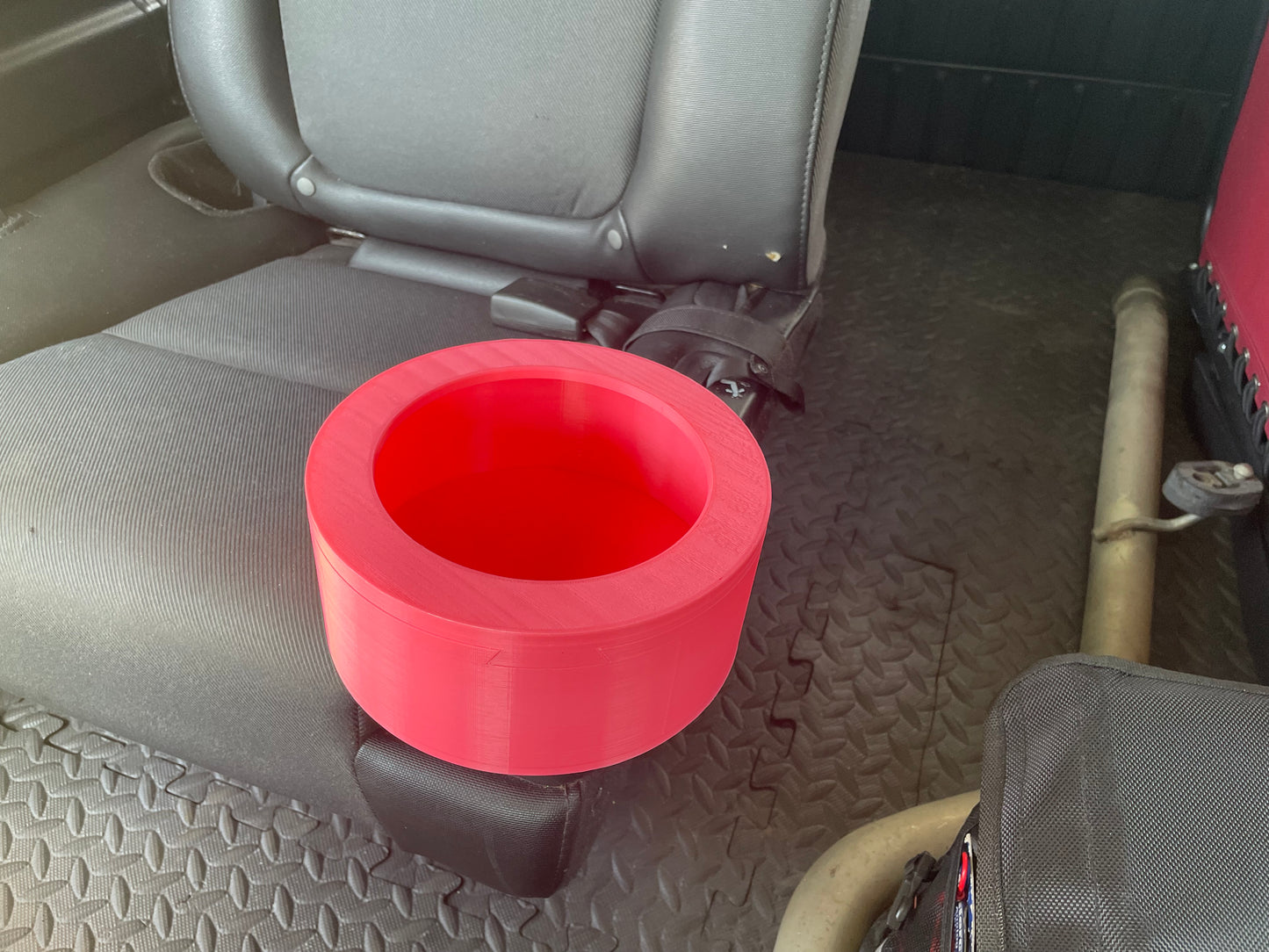 Red 3D printed car cup holder insert on a black car seat.