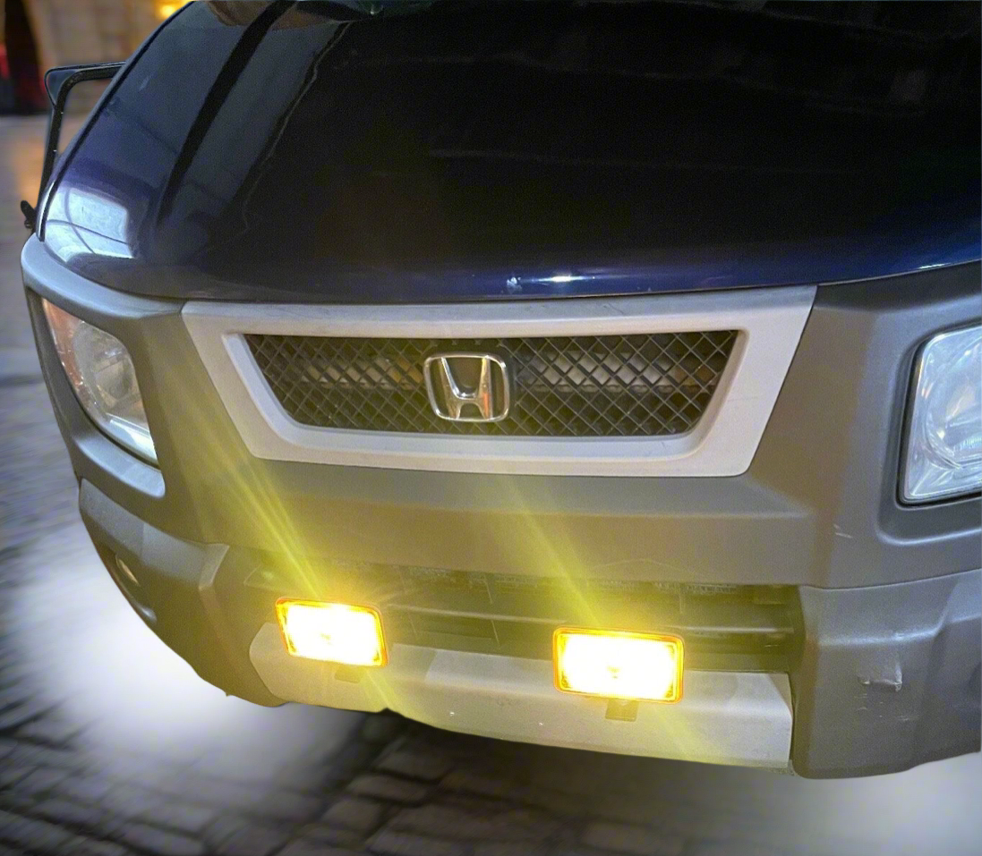 Front view of a blue car featuring a silver grill with the Honda logo and aftermarket yellow fog lights.
