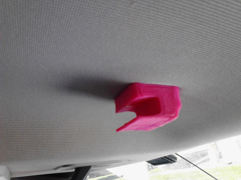 Pink 3D printed car visor clip attached to the car ceiling.