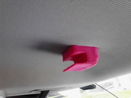 Pink 3D printed car visor clip attached to the car ceiling.