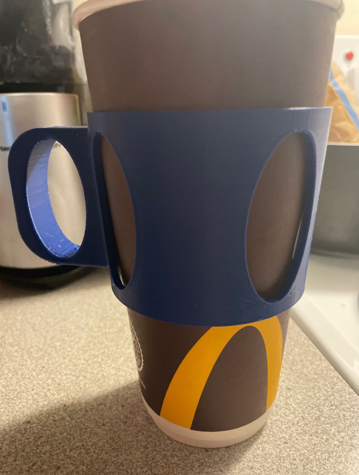 McDonald's coffee cup with a blue 3D printed handle holder for improved grip.