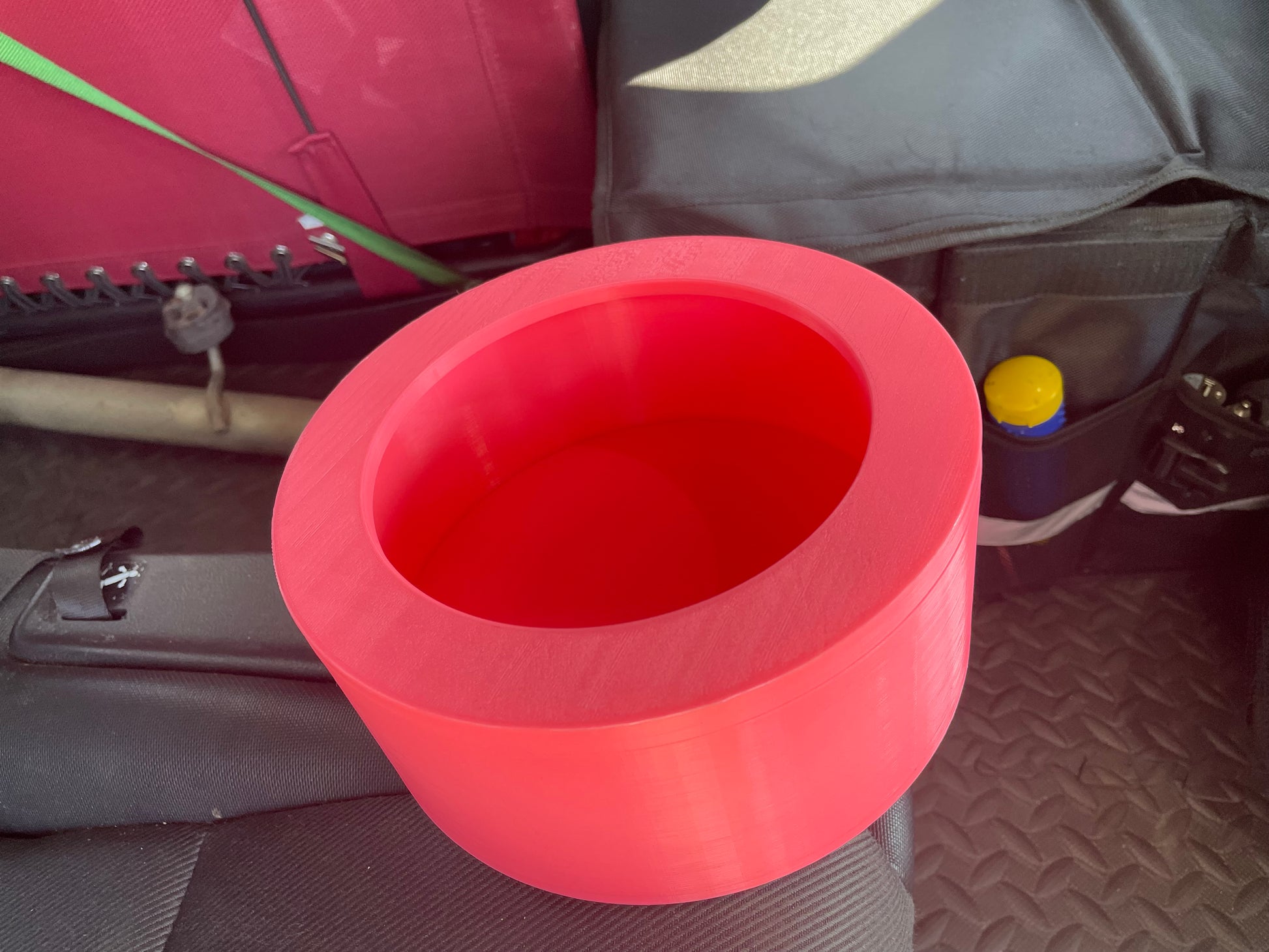 Red 3D printed ring light mount on car seat, close-up.