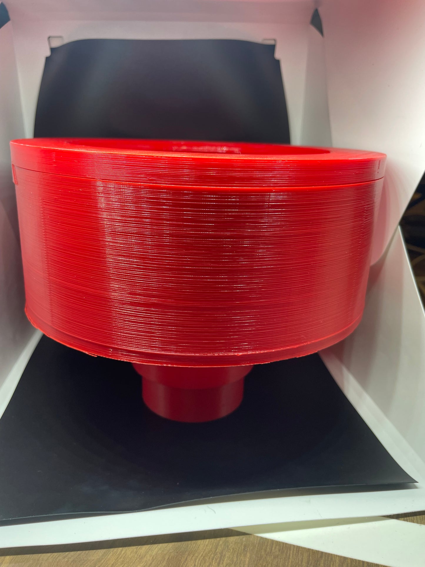 Red 3D printed cylinder with a funnel-shaped base.