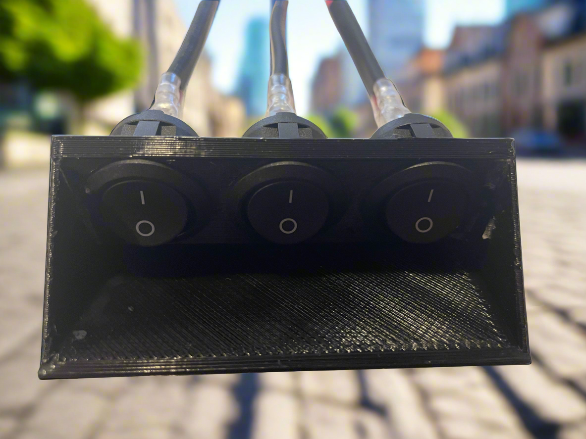 Black triple toggle switch box with wires. Close-up of a three-switch control panel.