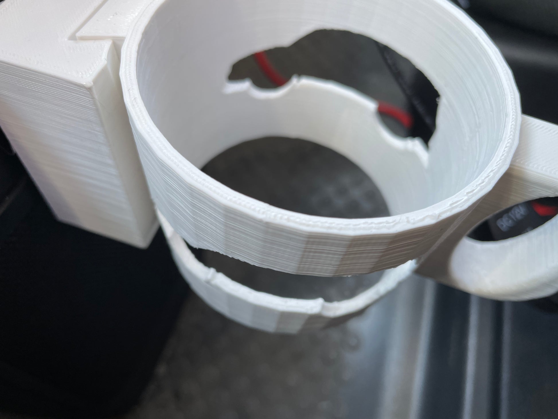 Close-up of a white 3D-printed car cup holder. Circular design with visible layer lines.