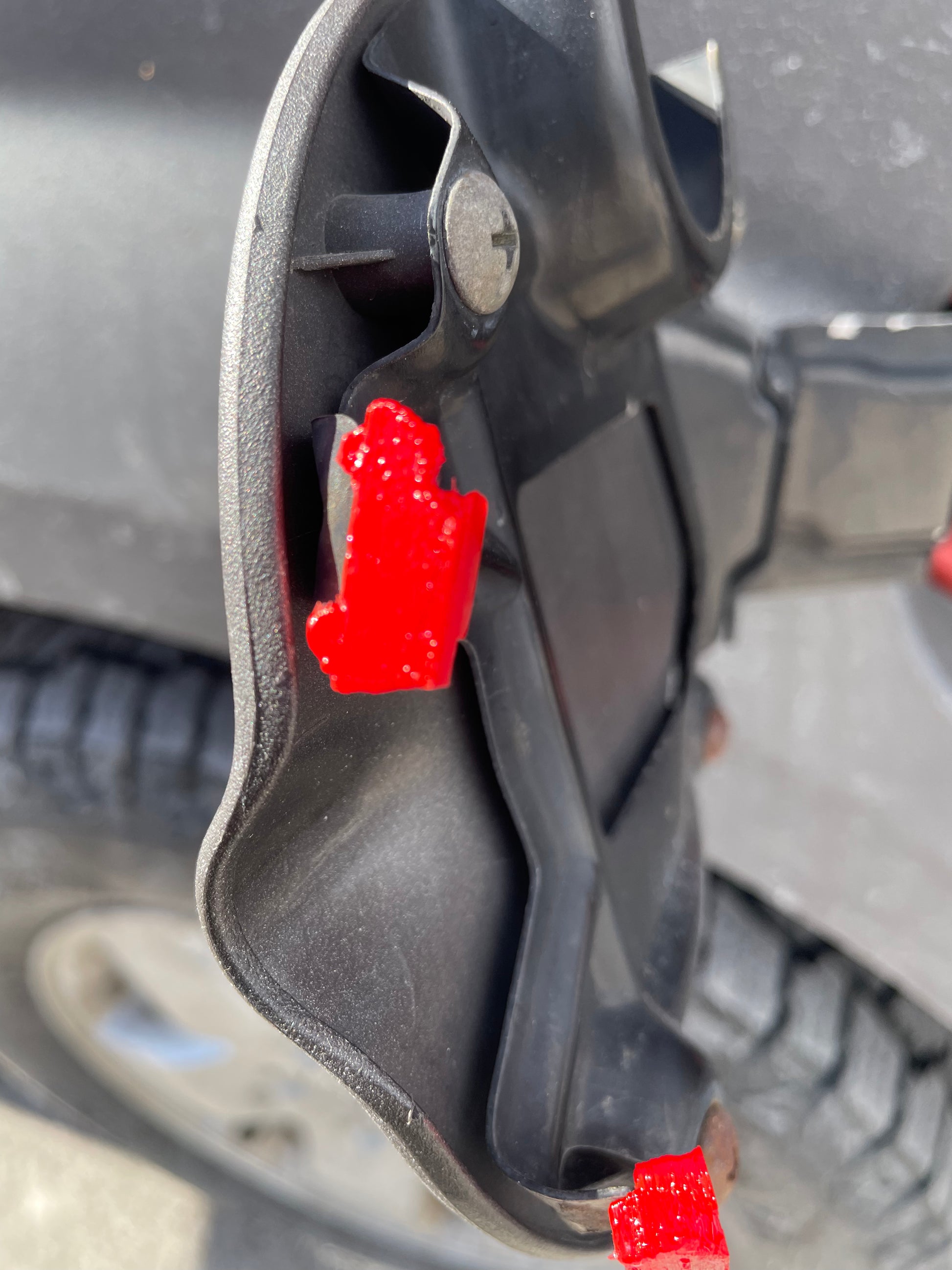 Close up of a black plastic car part with red reflectors.