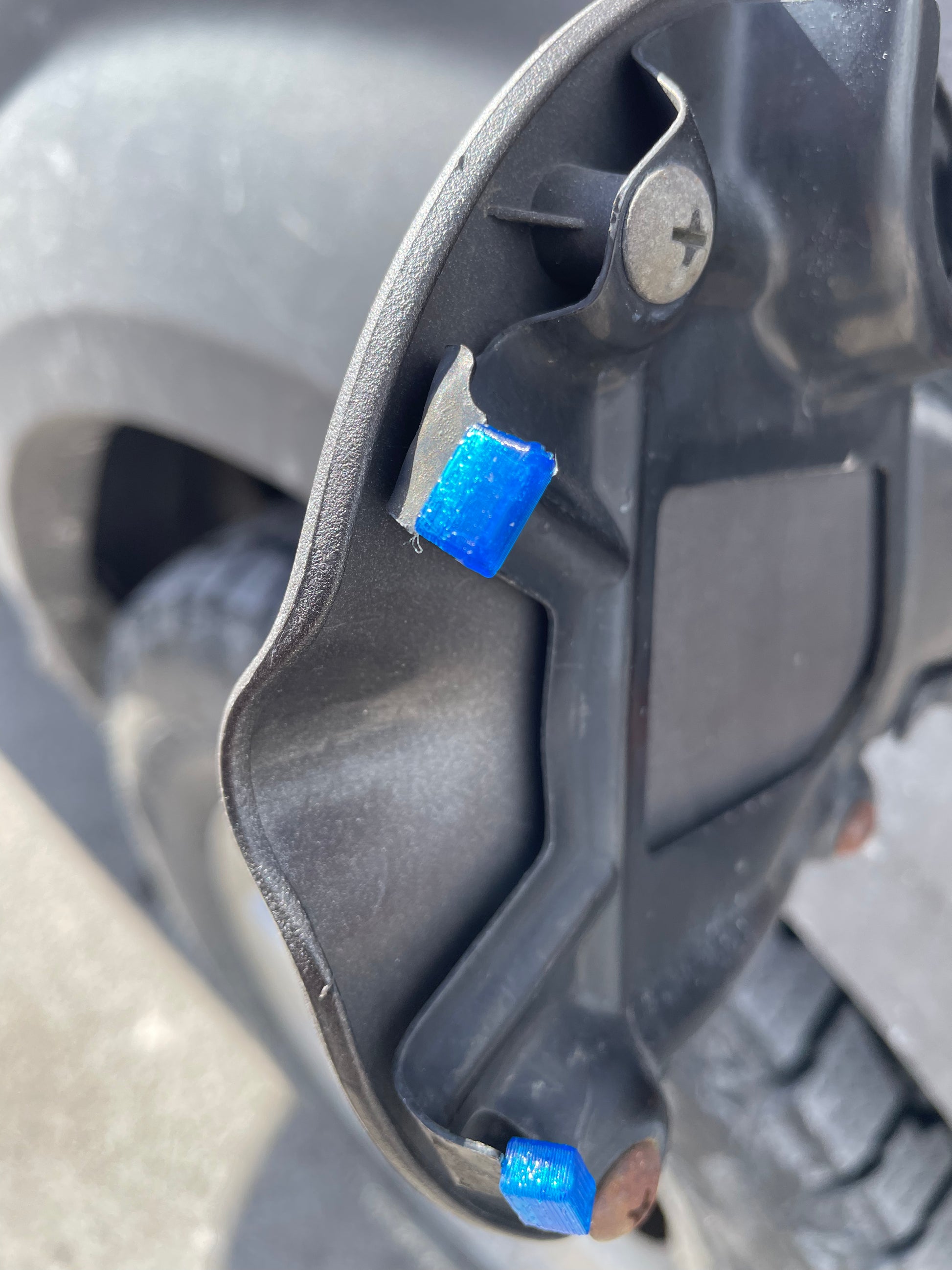 Close-up of a black gas cap cover with blue 3D-printed hinge fix.