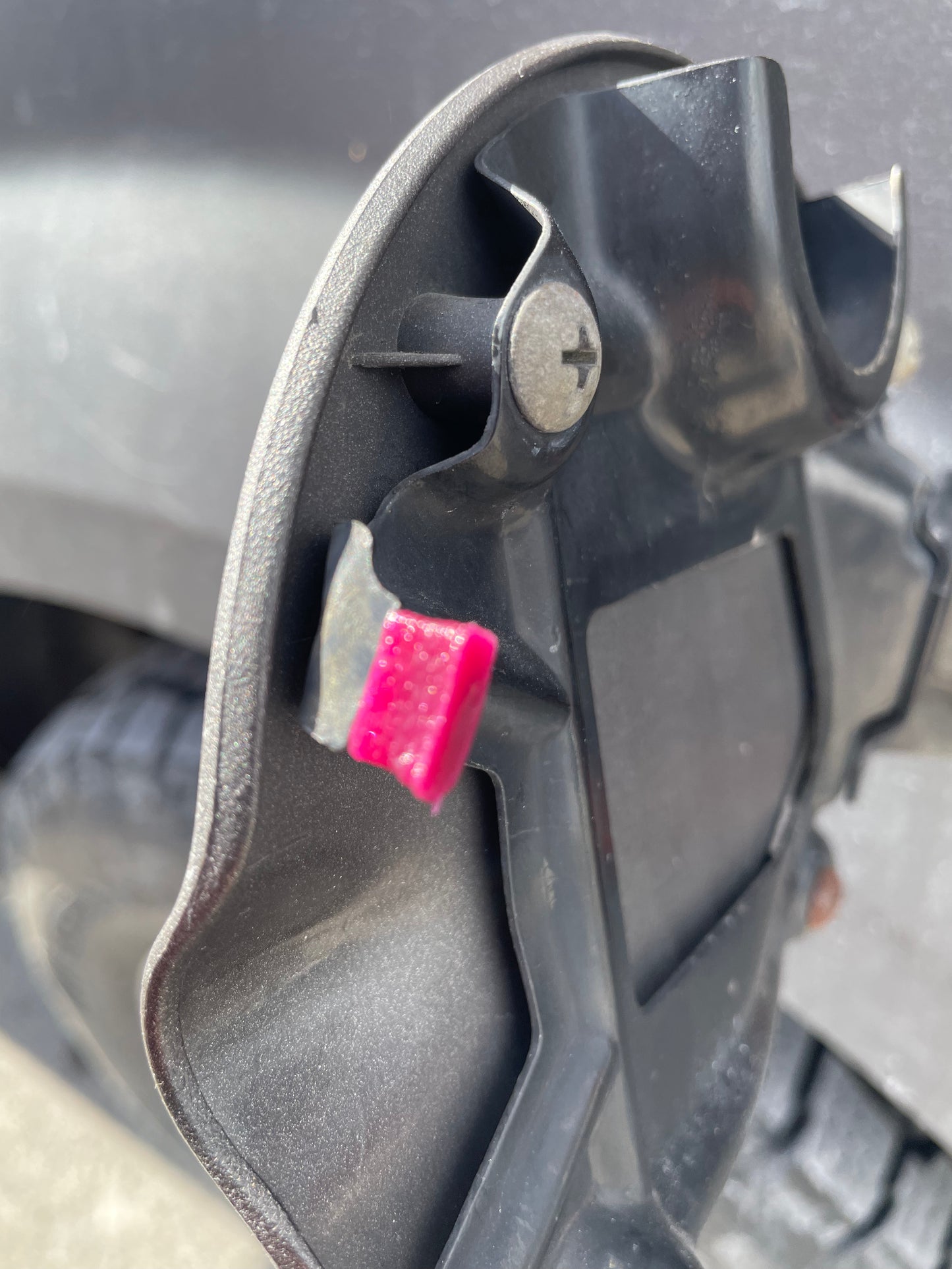 Close-up of a black vehicle mud flap with a pink adhesive patch.