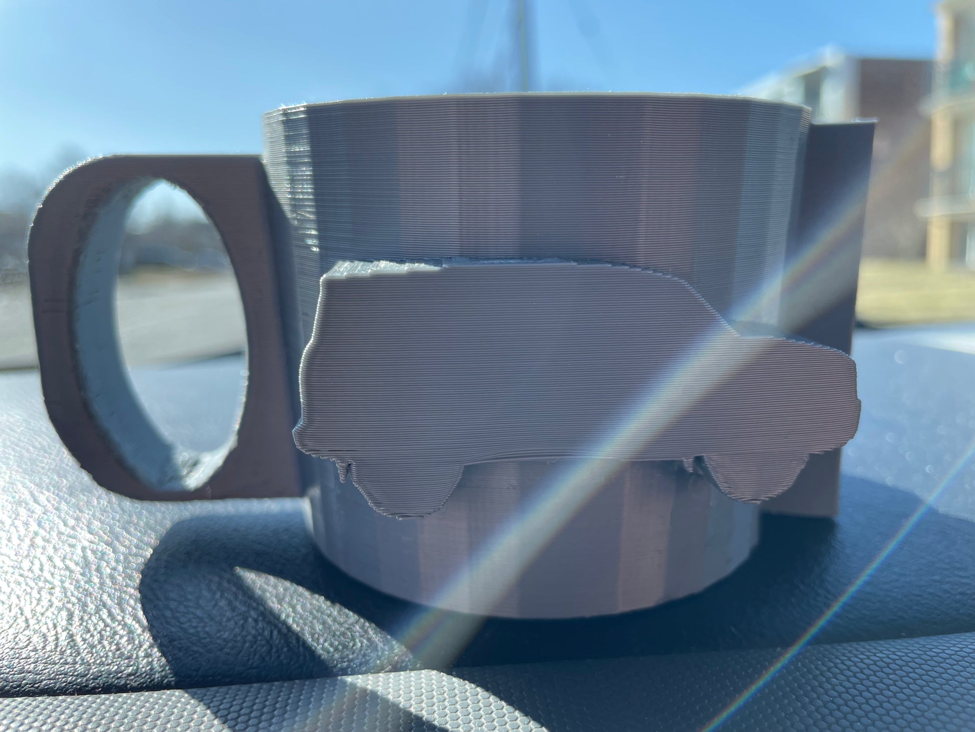 Gray 3D printed mug with car design.