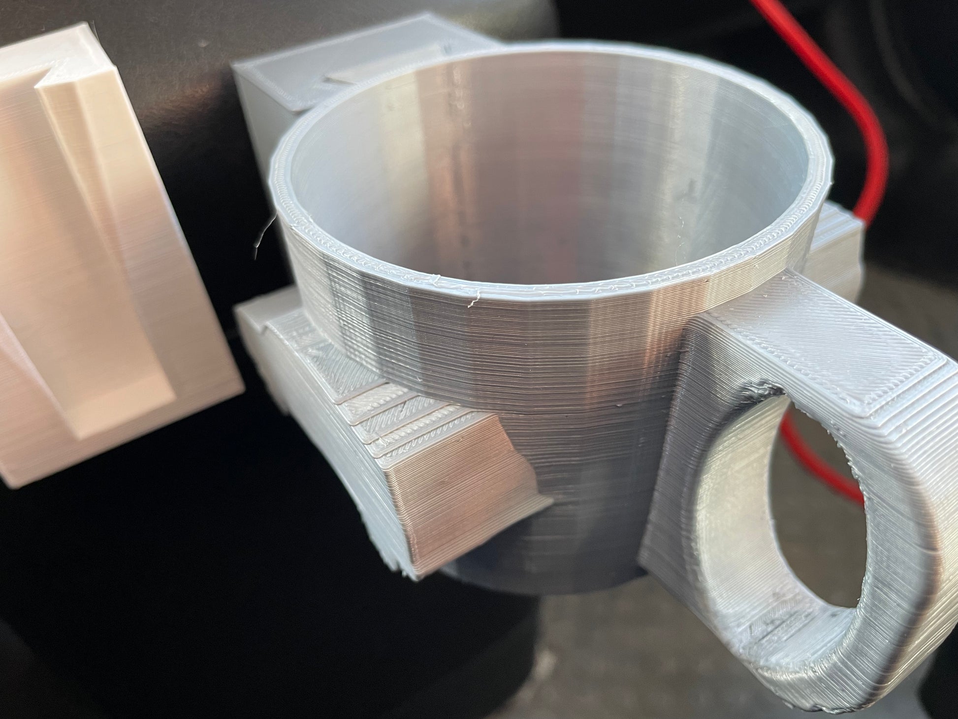 3D-printed silver cup holder with handle.