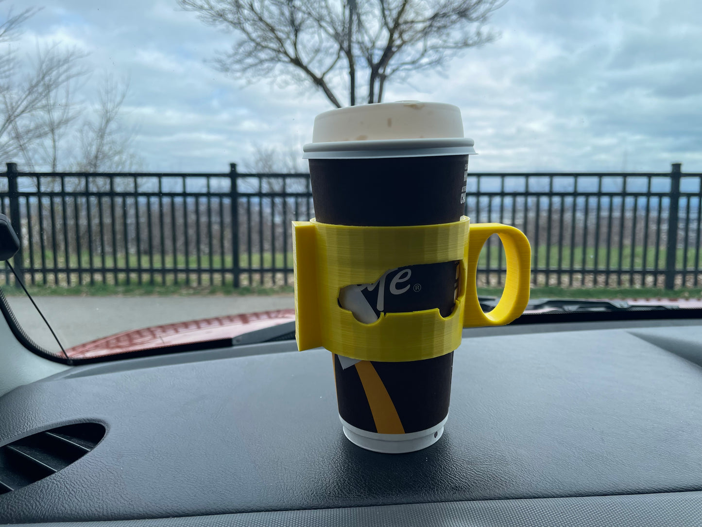 Coffee cup in a yellow 3D-printed holder in a car.