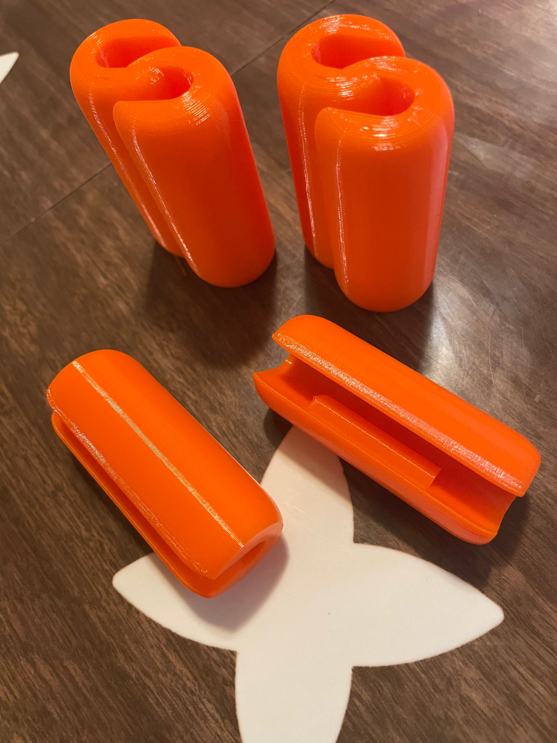 Orange 3D printed curtain rod connector clips.