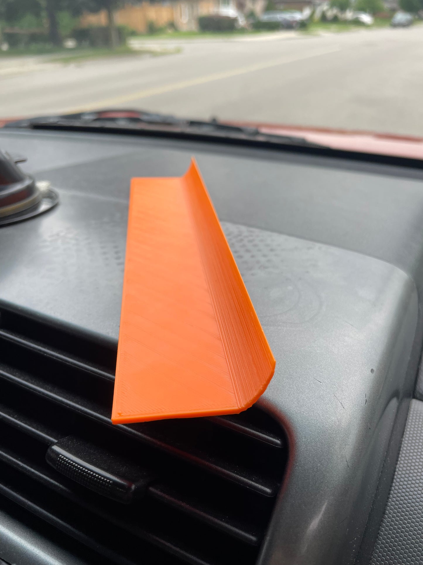 Orange 3D printed car dashboard trim piece on car vent.