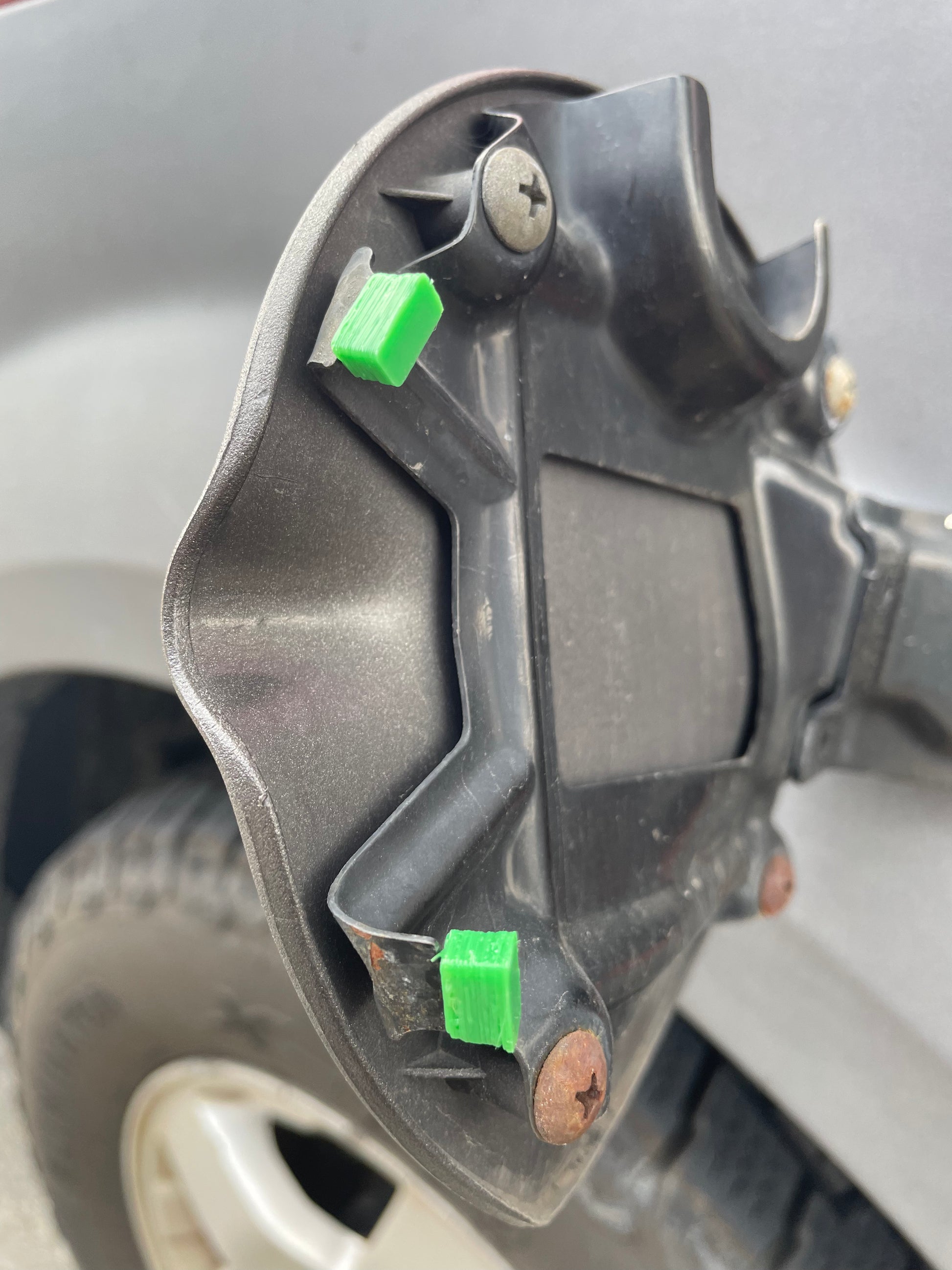 Close up of a vehicle's gas tank door with green door hinge bumpers.