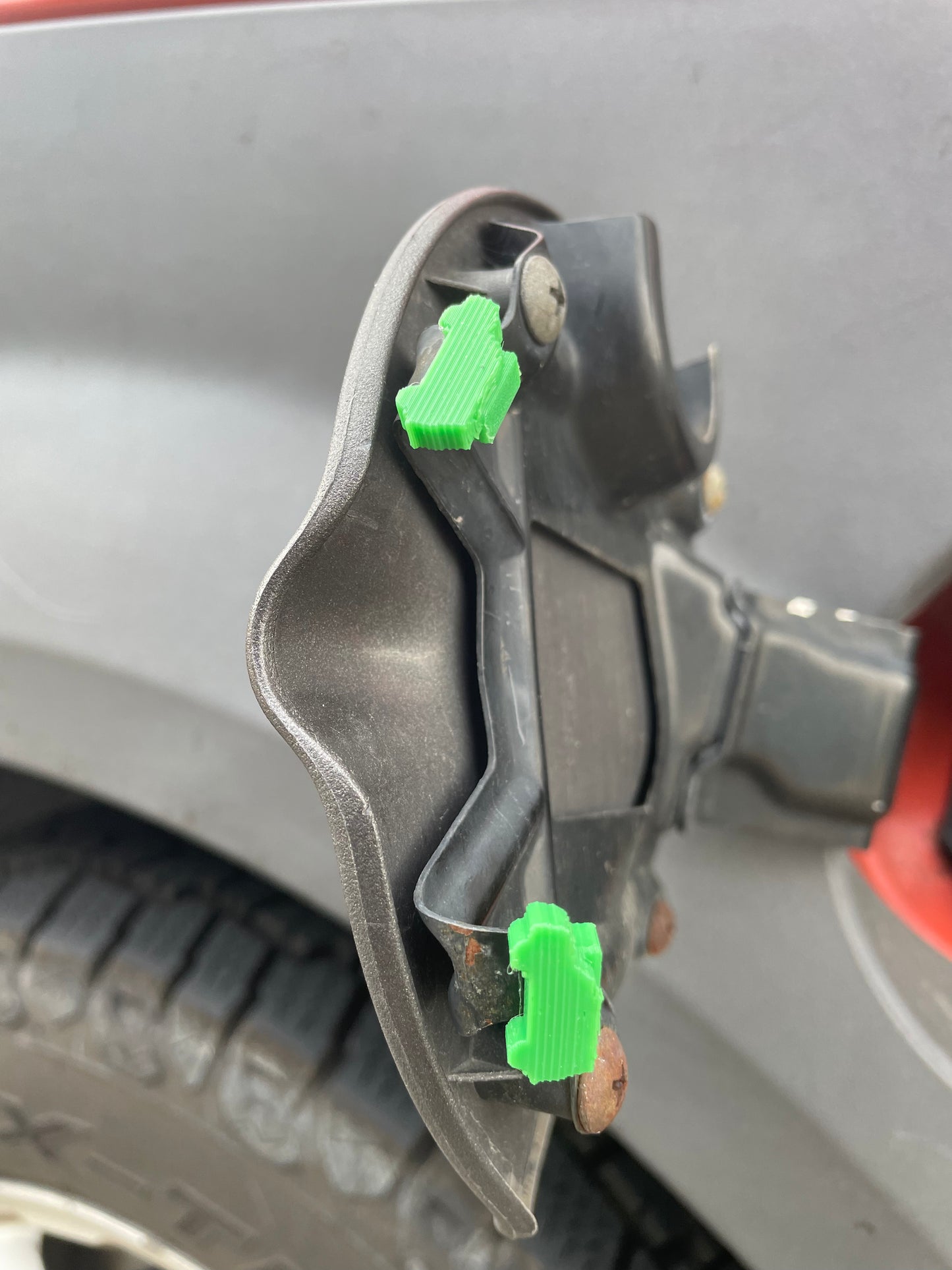 Car fuel door with green hinge repair clips.