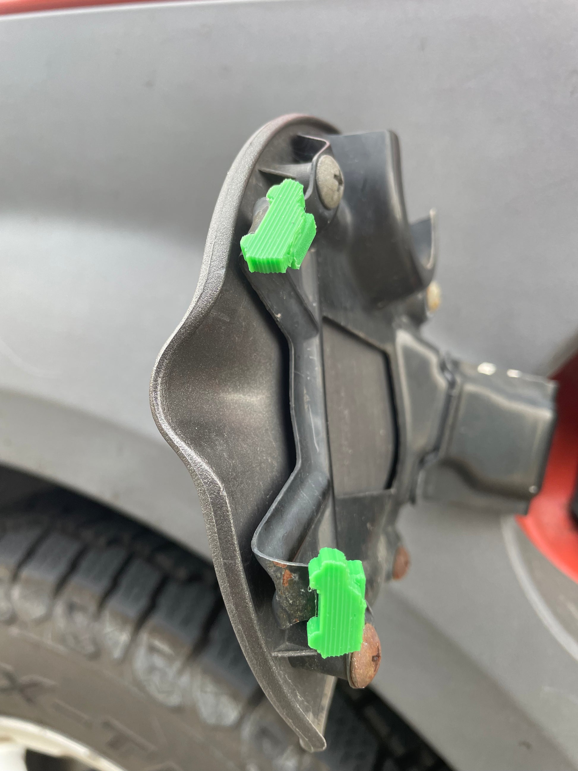 Car fuel door with green hinge repair clips.